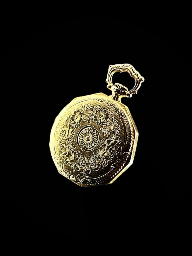 Engraved gold pocket watch back on black, lit with Halumin