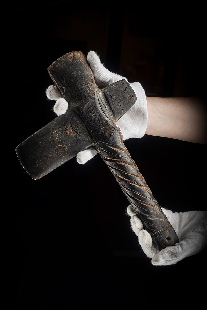Gloved hand holding a T-shaped carved stone artifact, lit with the Halumin H18 lighting device