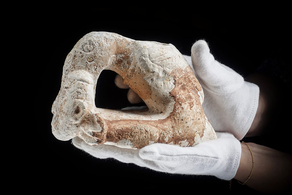 Carved stone pipe photographed from the side on black, museum artifact photography with the Halumin H18