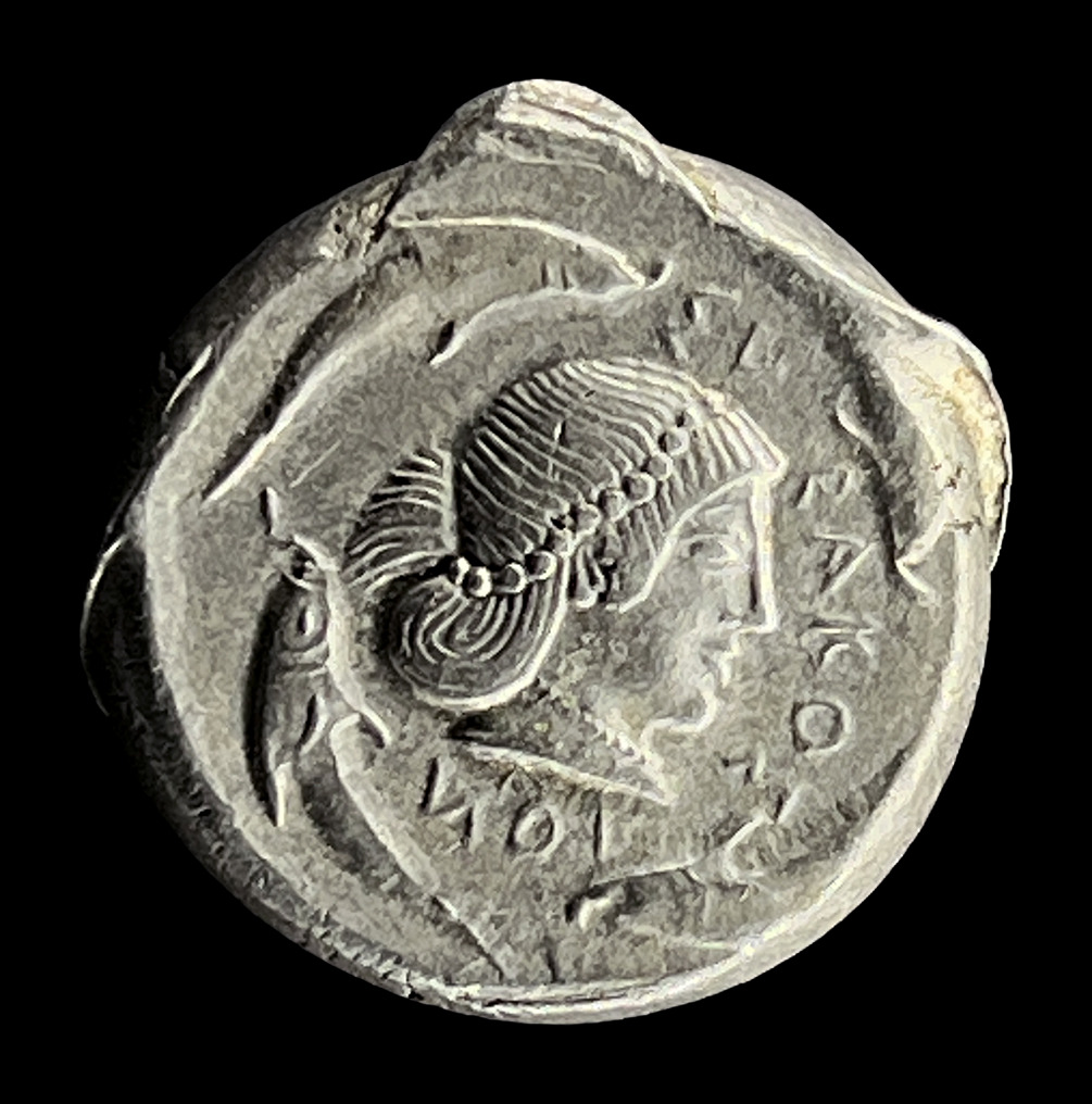 Ancient silver coin with a high-relief female head and dolphins, photographed on black with the Halumin-C and an iPhone