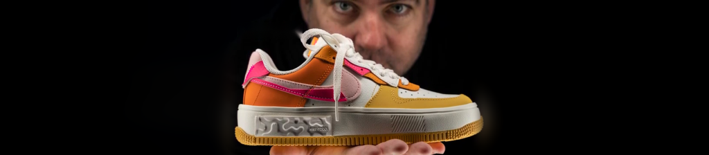 Nike Air Force 1 sneaker held on a hand against black, lit with the Halumin H18 lighting device
