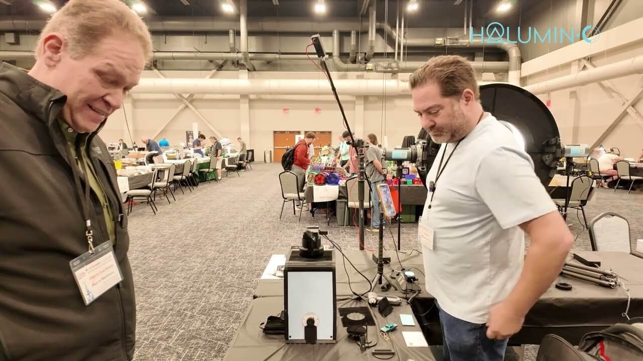 Collector watching as a toned coin is photographed with the Halumin-C and a phone at a Cincinnati coin show