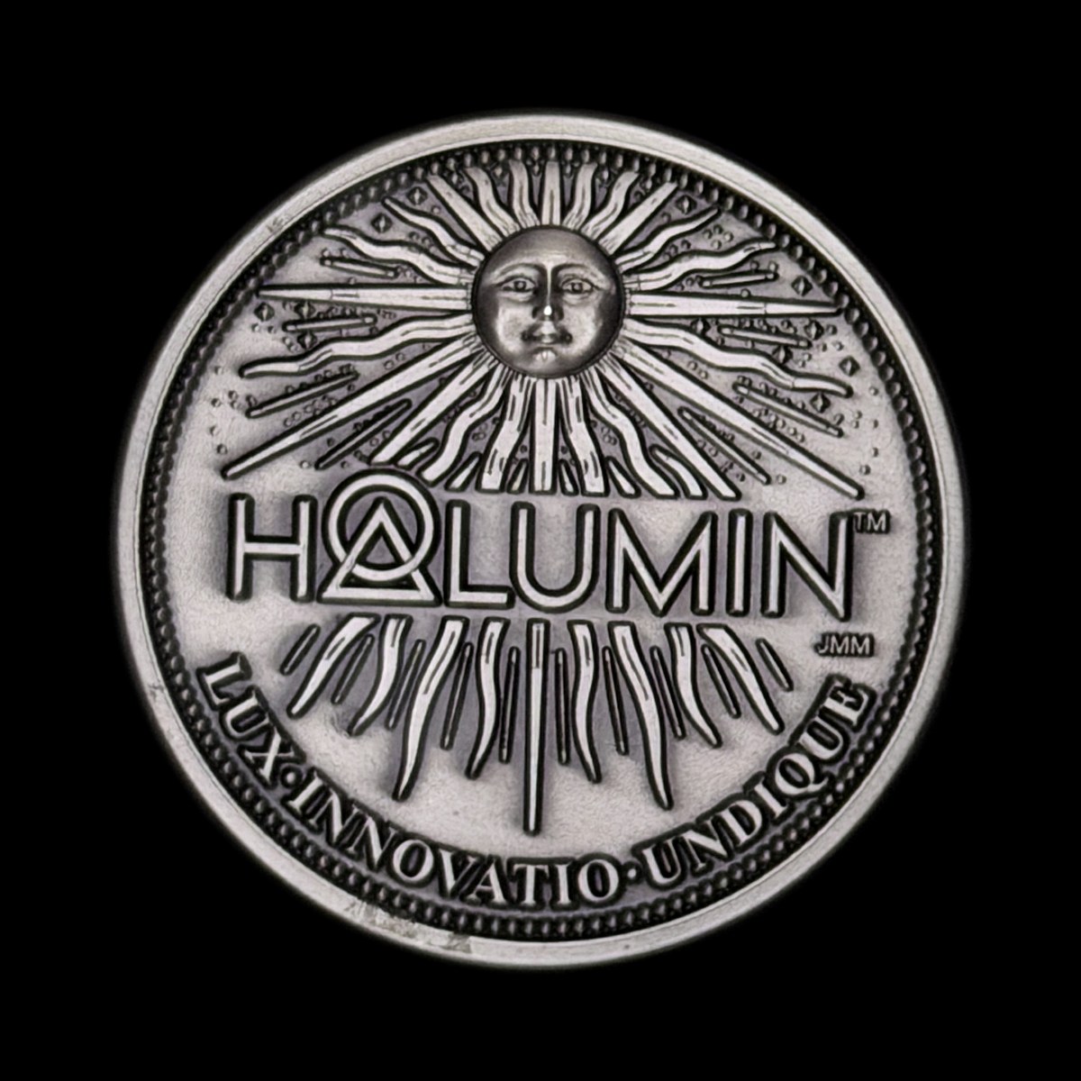 Sun face of the solid nickel Halumin coin with the words LUX INNOVATIO UNDIQUE, photographed on Halumin-C with an iPhone