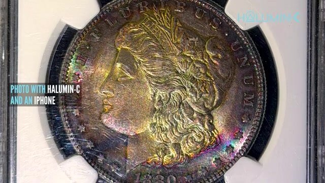 Rainbow-toned Morgan silver dollar in a slab, photographed with the Halumin-C and an iPhone